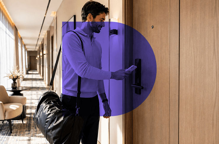 Business traveler unlocking a hotel room door with their phone while walking through the corridor